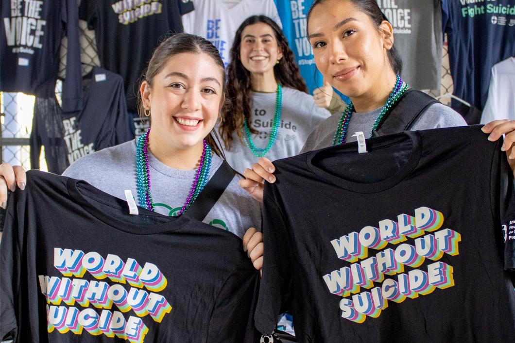 Women holding "World Without Suicide" shirts